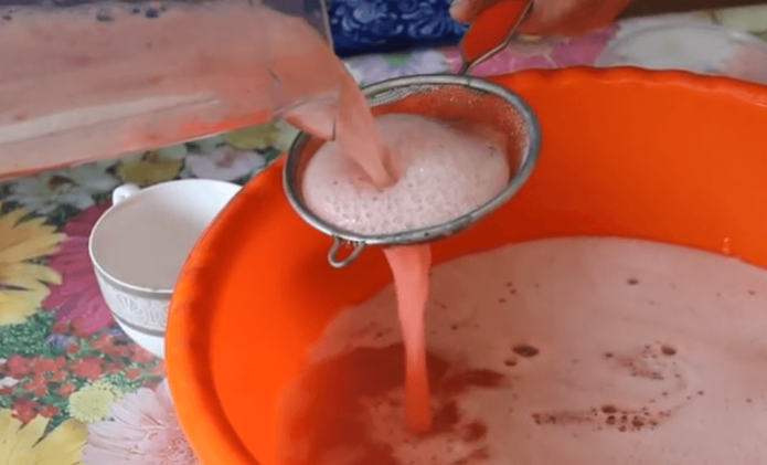 Straining the strawberry mixture through a strainer