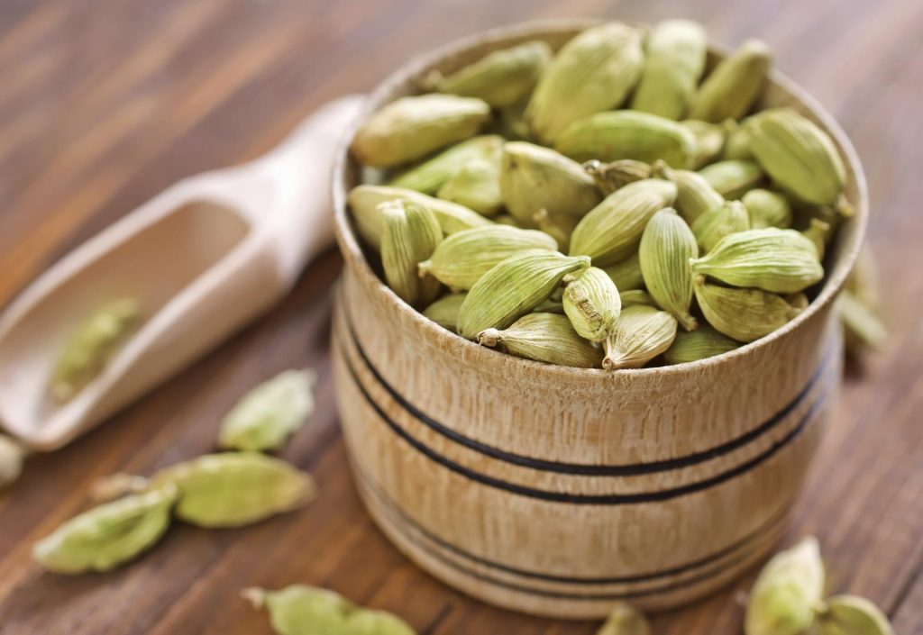 Cardamom seeds in wooden bowl and shovel